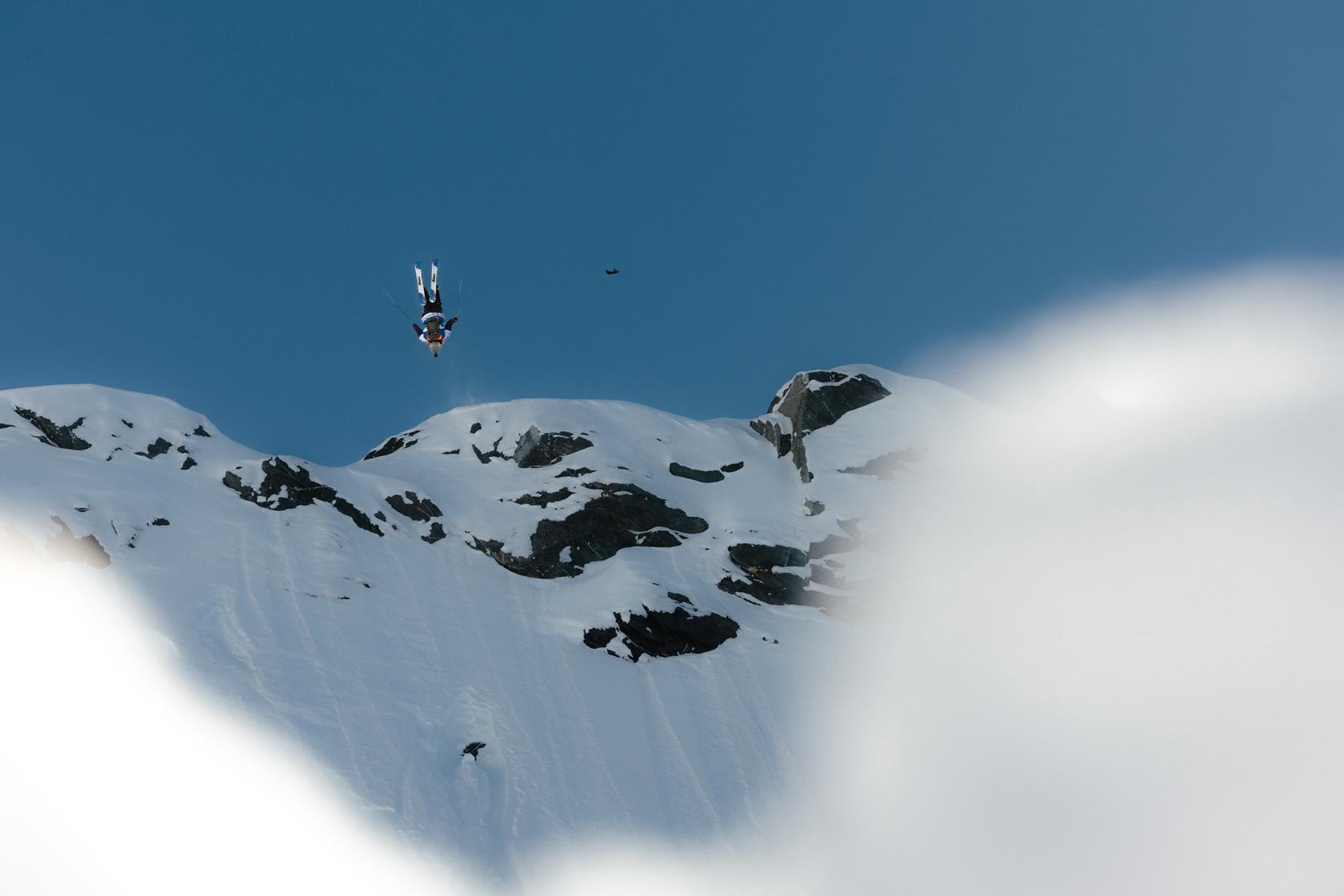 Freeride skier carving a powder spray down a steep alpine face